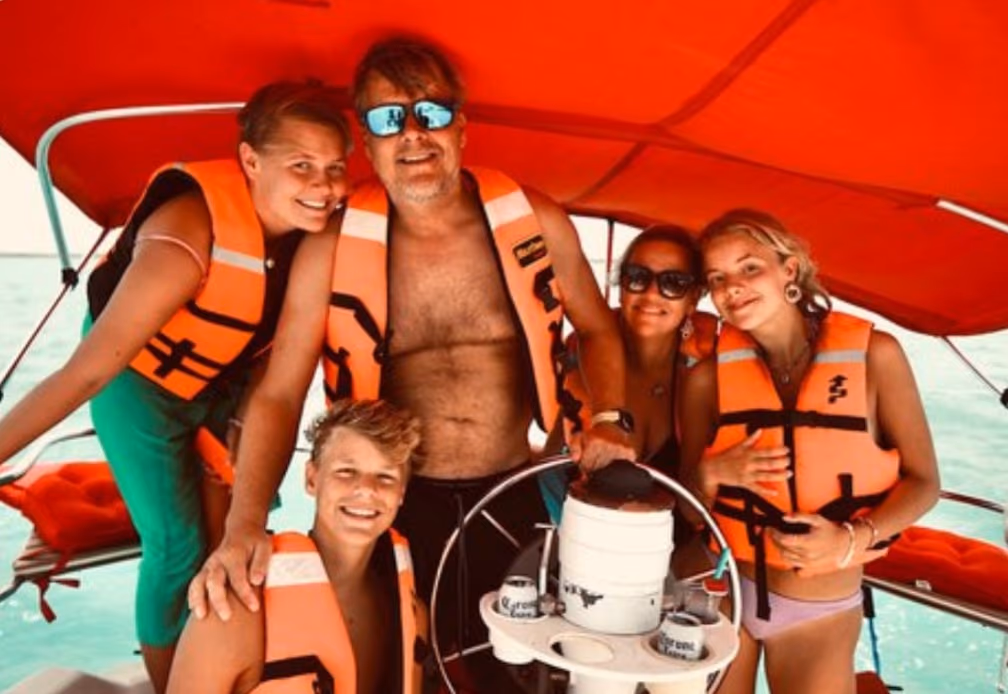 Familia con chalecos salvavidas al timón de un velero